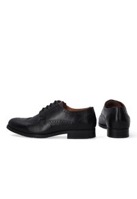 Zwarte leren dresschoenen met een ronde neus, decoratieve brogue-details, vetersluiting en een lage gestapelde hak.