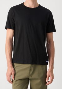 Sort kortærmet t-shirt, rund halsudskæring, blødt bomuldsstof, afslappet pasform, har blå "Hugo" logo på venstre side forneden.