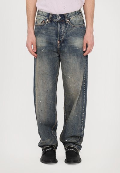 Jeans din denim albastru cu o croială lejeră, având zone decolorate și detalii cu stropi de vopsea. Talie cu nasture metalic și cuie.
