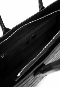 Borsa tote nera in pelle con finitura testurizzata, dotata di chiusura con zip, ampio interno e una tasca con zip aggiuntiva.