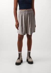 Light grey, knee-length shorts with an elastic waistband, paired with cream lace-up ankle boots featuring a chunky sole.