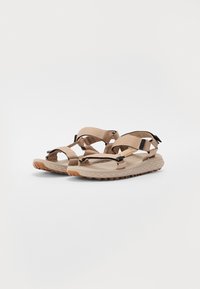 Beige kinti szandálok állítható pántokkal, gumitalppal, mely tapadó mintázattal rendelkezik, és kényelmes, formázott talpbéléssel.