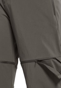 Close-up van grijze broek met afritsbare pijp en ritssluiting.