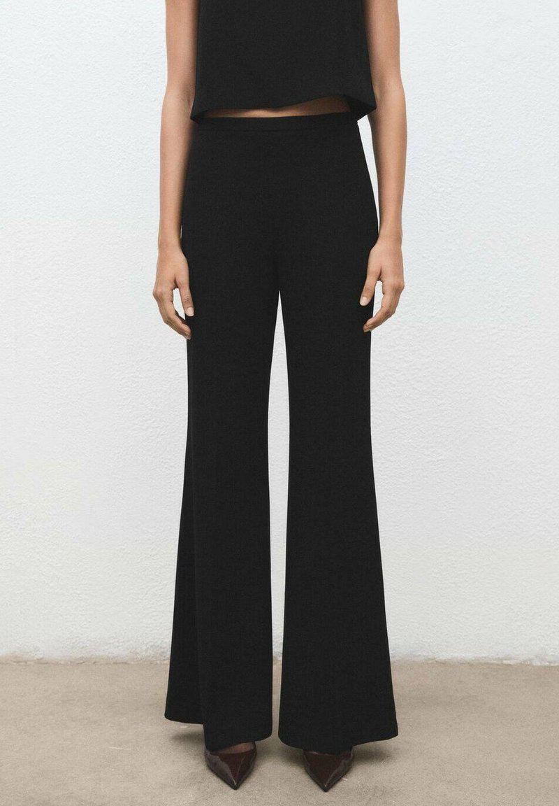 Pantalones acampanados negros de talle alto hechos de un material liso, con un corte de longitud completa y una silueta fluida.