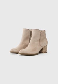 Beige semskede ankelsko med rund tå, sideglidelås og en teksturert stablet hæl. Glatt overflate med minimale detaljer.