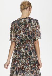 Bluse mit Blumenmuster aus transparentem Material, ausgestattet mit kurzen Ärmeln, Rundhalsausschnitt und mehrlagigem Design in verschiedenen Farben wie Grün, Pink und Blau.