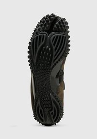 Ελαστική σόλα αθλητικού παπουτσιού με υφή και σπυριά πρόσφυσης, διαθέτοντας καμουφλαριστό άνω μέρος και μαύρες λεπτομέρειες.