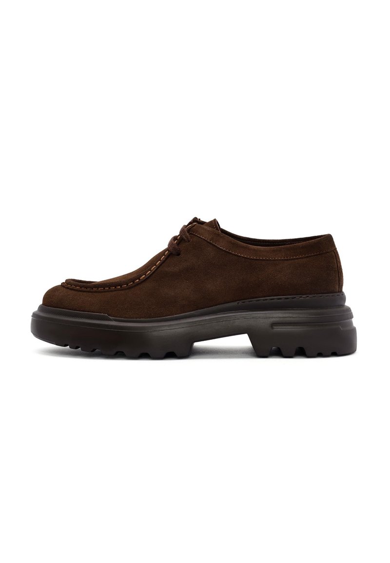 Scarpe in suede marrone con profilo basso, punta rotonda e cuciture a contrasto. Suola in gomma spessa e robusta progettata per offrire aderenza.