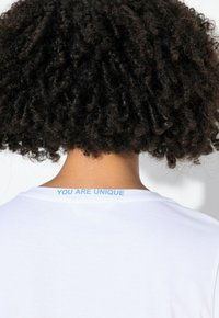 Hvid bomulds t-shirt med rund hals, med lyseblå tekst "YOU ARE UNIQUE" på bagsiden af halsudskæringen. Blød tekstur og klassisk snit.