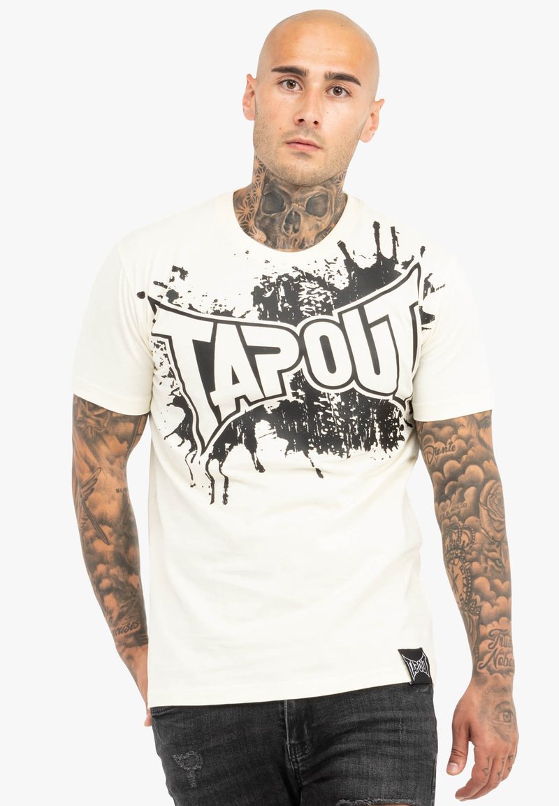Hvid T-shirt med et stort sort "TAPOUT" grafisk motiv med splatterdesign. Korte ærmer, rund hals og et mærke på den nederste side.