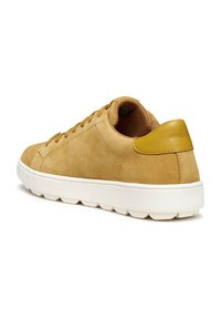 Sneaker in suede tan con punta rotonda, tomaia texture e suola in gomma bianca. Presenta un accento giallo sul tallone e sei fori per i lacci.