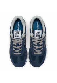Marinblå sportskor med mesh- och mockaöverdel, grå snören och vit sula. Har "New Balance Classic 574"-etikett på tungan.