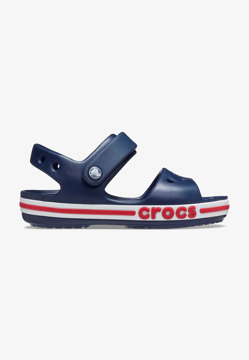Sandale Crocs bleu marine avec un design ouvert, semelle rayée rouge et blanche, sangle ajustable et trous de ventilation pour une meilleure respirabilité.