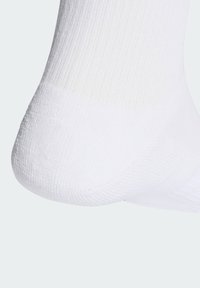 Chaussette blanche présentant une texture côtelée, un talon renforcé et une partie supérieure en maille lisse. Le matériau semble doux et extensible, conçu pour le confort.