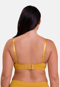 Soutien-gorge jaune avec des bretelles réglables, tissu texturé et fermeture à plusieurs crochets à l'arrière. Design simple adapté à un port quotidien.