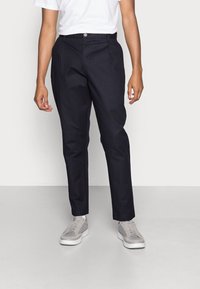 Skräddarsydda navybyxor i slät tyg, med knäppning, sidofickor och raka ben. Stylingen kompletteras med grå sneakers.