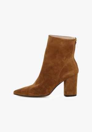 Bruine suède enkellaarsjes met een spitse neus, chunky hak en zijrits. Glad textuur met minimale stikselaccenten.