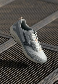 Light grey athletic shoe featuring mesh and synthetic materials, rounded toe, black accents, and a textured outsole.