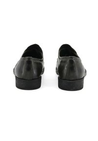 Scarpe in pelle nera con texture liscia, tacco basso, forma arrotondata e dettagli cuciti sul retro. La suola sembra leggermente usurata.