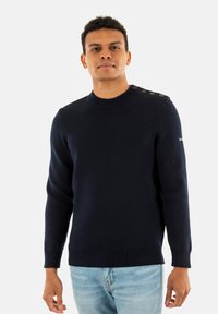 Maglione blu navy con collo rotondo, polsini e orlo a costine, caratterizzato da bottoni decorativi sulla spalla e tessuto testurizzato.