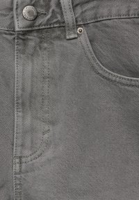 Jeans de mezclilla gris con un diseño clásico de cinco bolsillos, un botón de metal con la marca y costuras tonales en una tela suave.