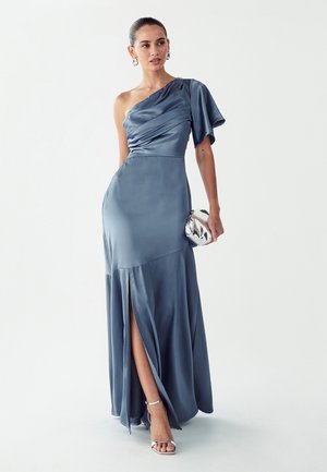 Ühe õlaga satiinist kleit pehmes sinises toonis, millel on drapeeritud disain, külje lõhik ja voolav ääreosa. Kombineeritud hõbedase klapi ja kontsakingadega.