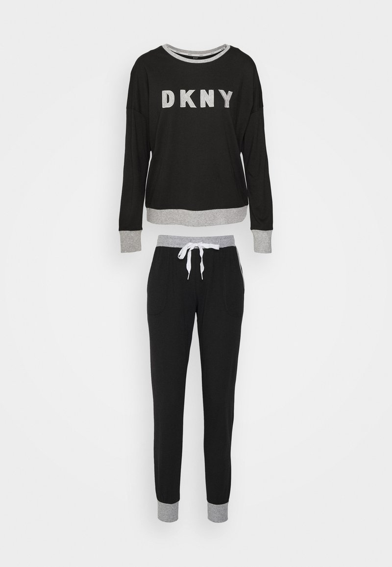 Sudadera negra de DKNY con acentos y letras grises, combinada con pantalones jogger negros que tienen cordón y puños grises. Textura de tela suave.