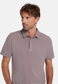 Korte mouwen polo shirt in licht mauve stof, met een omklapkraag en een knoopsluiting met twee knopen. Gladde, gestructureerde breistekstuur.