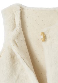 Cremefarbener Kunstfellweste mit kleinen goldenen Punkten im Innenfutter und einem Klickverschluss.