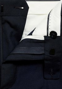 Marinejacke mit einem weißen Innenfutter, ausgestattet mit einem Reißverschluss, Knopfverschluss und gesteppten Details. Glattes Gewebe mit einer strukturierten Haptik.