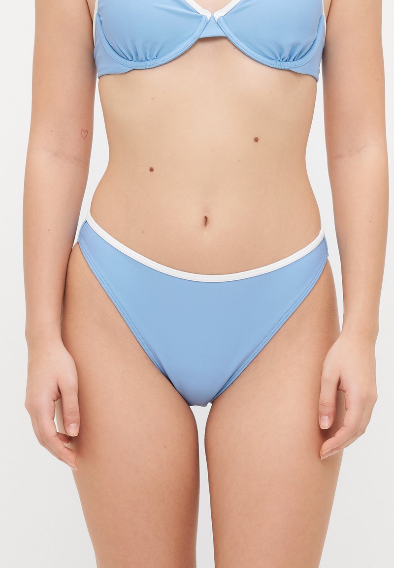 Zils bikinī tops ar vieglu pildījumu un baltu apdari, pārī ar atbilstošiem zemu vidukļa bikinī apakšā. Gluda, stiepjama auduma ar pieguļošu dizainu.