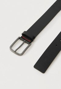 Black leather belt with a textured finish, featuring a silver metal buckle and red stitching on the keeper loop. Simple and functional design.