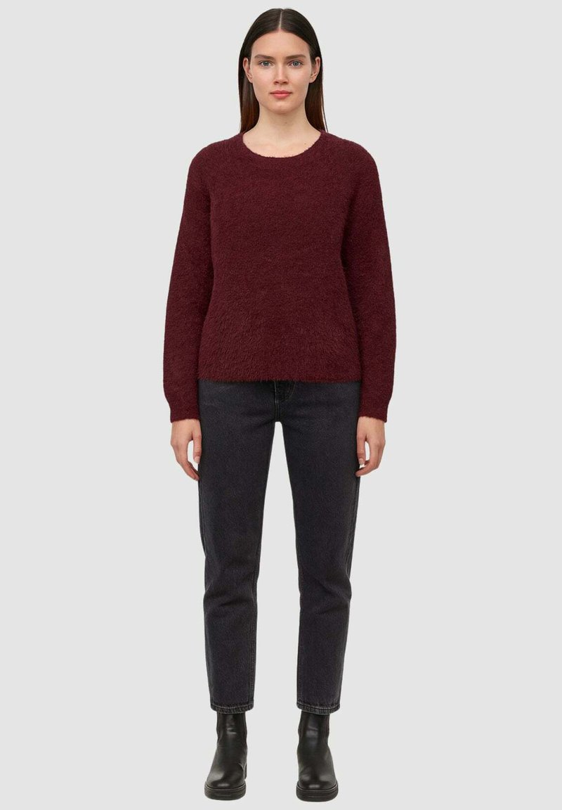 Maglione borgogna peloso con maniche lunghe e scollatura rotonda, abbinato a jeans neri a gamba dritta e stivaletti neri.