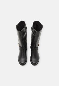 Bottes noires en cuir, montantes jusqu'au genou, avec une texture lisse, dotées d'une fermeture éclair sur le côté et d'un accent doré près de la cheville.