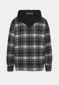 Felpa con cappuccio in bianco e nero, caratterizzata da un motivo a quadri con tonalità variabili, cappuccio nero e polsini a coste. Texture morbida e design casual.