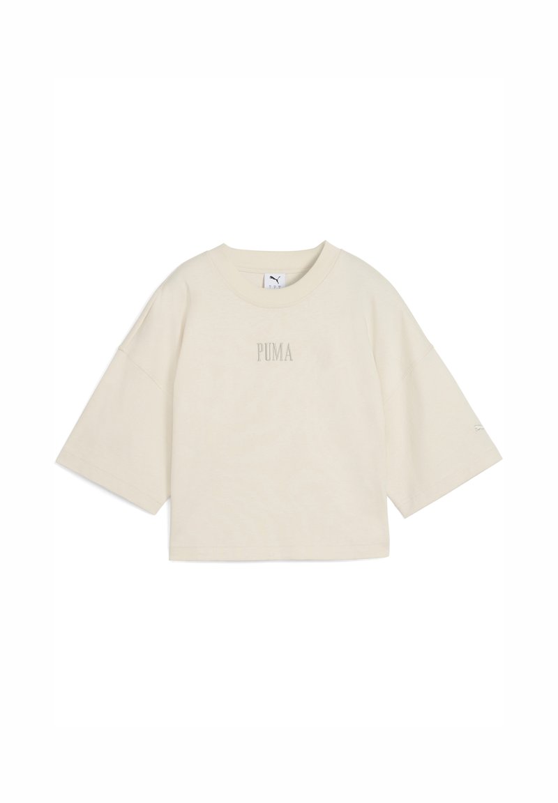 Lys beige kortærmet t-shirt lavet af blød bomuld. Har en rund halsudskæring og et lille "PUMA" logo i midten. Boksformet silhuet.