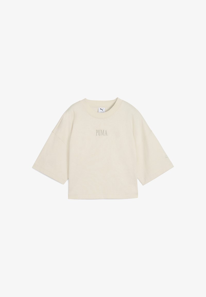Lys beige kortærmet t-shirt lavet af blød bomuld. Har en rund halsudskæring og et lille "PUMA" logo i midten. Boksformet silhuet.