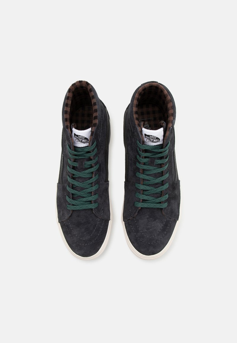 Zapatillas altas de ante gris oscuro con cordones verdes. Forro a cuadros marrón y suelas de goma blanca. Detalles de costura visibles en todo el diseño.