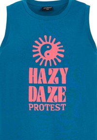 Mėlynas medvilninis trumpas topas su dideliu rožiniu saulės ir yin-yang piešiniu, užrašu "HAZY DAZE PROTEST" menišku šriftu.