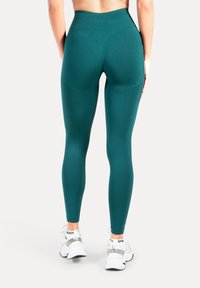 Leggings d'un bleu sarcelle taille haute avec une texture lisse et une coupe ajustée, dotés d'une large ceinture et sans coutures visibles.