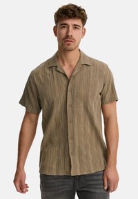 Korte mouwen button-up shirt in een gestructureerde olijfgroene stof met een relaxte pasvorm en ingesneden kraag, met opvallende knopen aan de voorkant en subtiele lijnen.