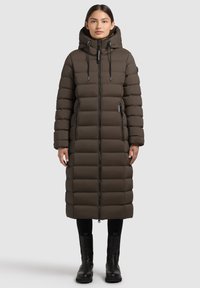 Cappotto imbottito di media lunghezza, marrone scuro, con cappuccio, chiusura con zip e due tasche laterali. Presenta sezioni trapuntate e coulisse regolabili.