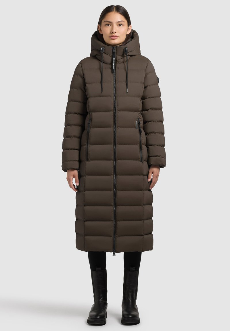 Cappotto imbottito di media lunghezza, marrone scuro, con cappuccio, chiusura con zip e due tasche laterali. Presenta sezioni trapuntate e coulisse regolabili.