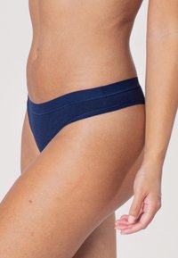 Navy blauwe bikini onderkant met een smalle tailleband, een gladde textuur, minimale bedekking en geen zichtbare patronen of versieringen.
