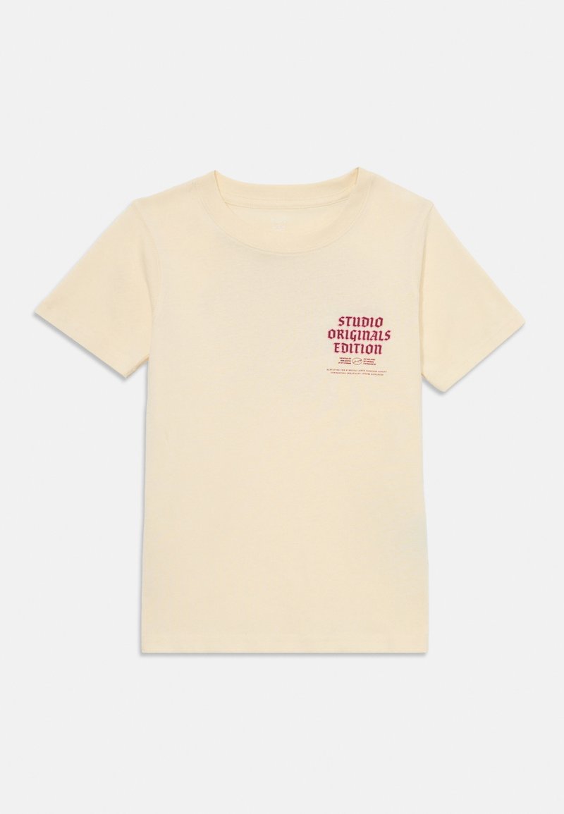 Gaismas krēma krāsas kokvilnas T-krekls ar īsām piedurknēm un apaļu kakla izgriezumu, ar sarkanu drukātu dizainu un tekstu kreisajā krūšu pusē.