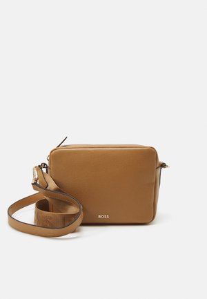 Brun læder crossbody taske med rektangulær form, der har en lynlås i toppen, hardware i guldfarve og en mærket rem til justerbar længde.