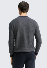 Navyfarbener strukturierter Pullover mit Rundhals und gerippten Ärmeln, ausgestattet mit einem kleinen gewebten Muster. Die Rückansicht zeigt ein tailliertes Design.