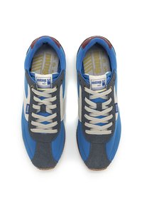 Sneakers blu e grigi con una superficie liscia, caratterizzati da accenti bianchi a contrasto, lacci rotondi e una suola in gomma. Logo del marchio visibile sulla linguetta.