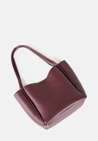 Burgundy leather tote bag with a smooth texture, wide body, and two shoulder straps. Features a soft, scalloped top edge and minimalist design.