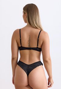 Black lace lingerie set featuring a bra with adjustable straps and hook closure, paired with a high-cut thong showcasing floral patterns.